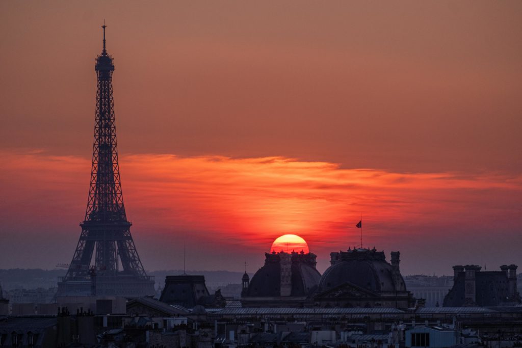 Sortir en groupe à Paris - toits parisiens au premier plan, Tour Eiffel au second plan et coucher de soleil en arrière plan 